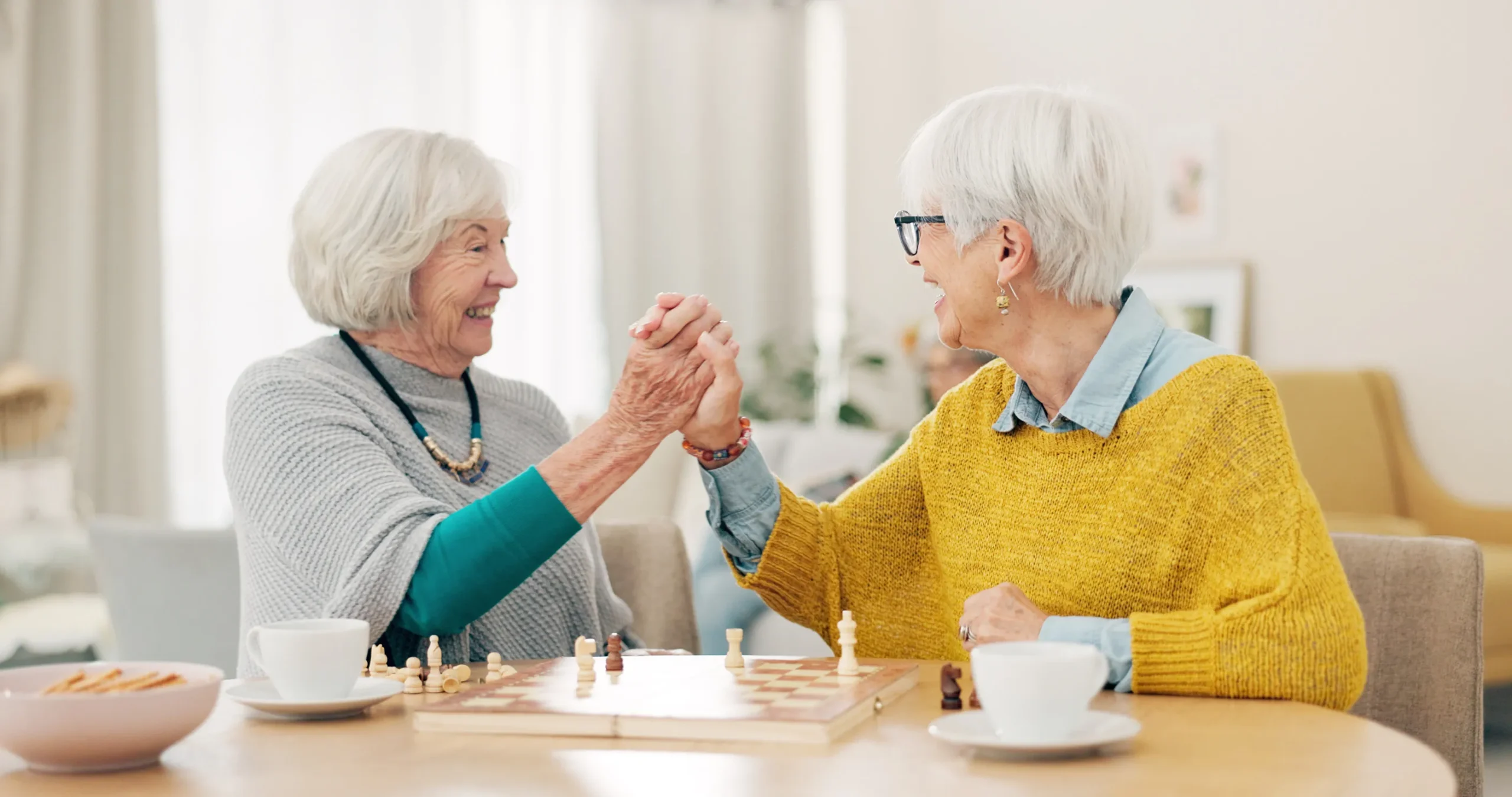 Senior woman, friends and high five for chess match, game or winning on table together at home Senior woman, friends and high five for chess match, game or winning on table together at home